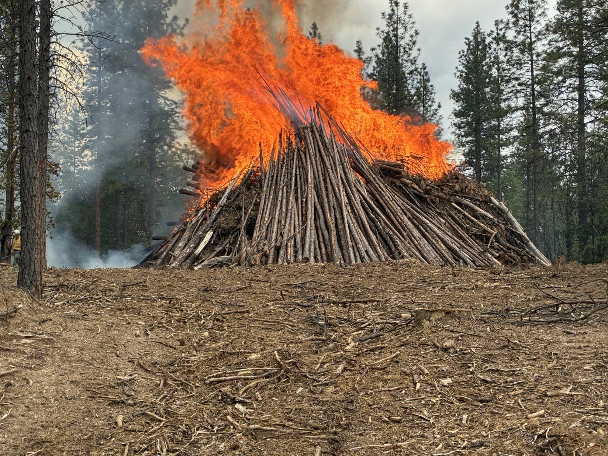 A machine pile fully involved in orange flame on Day 1 of the 'Inimim pile burn